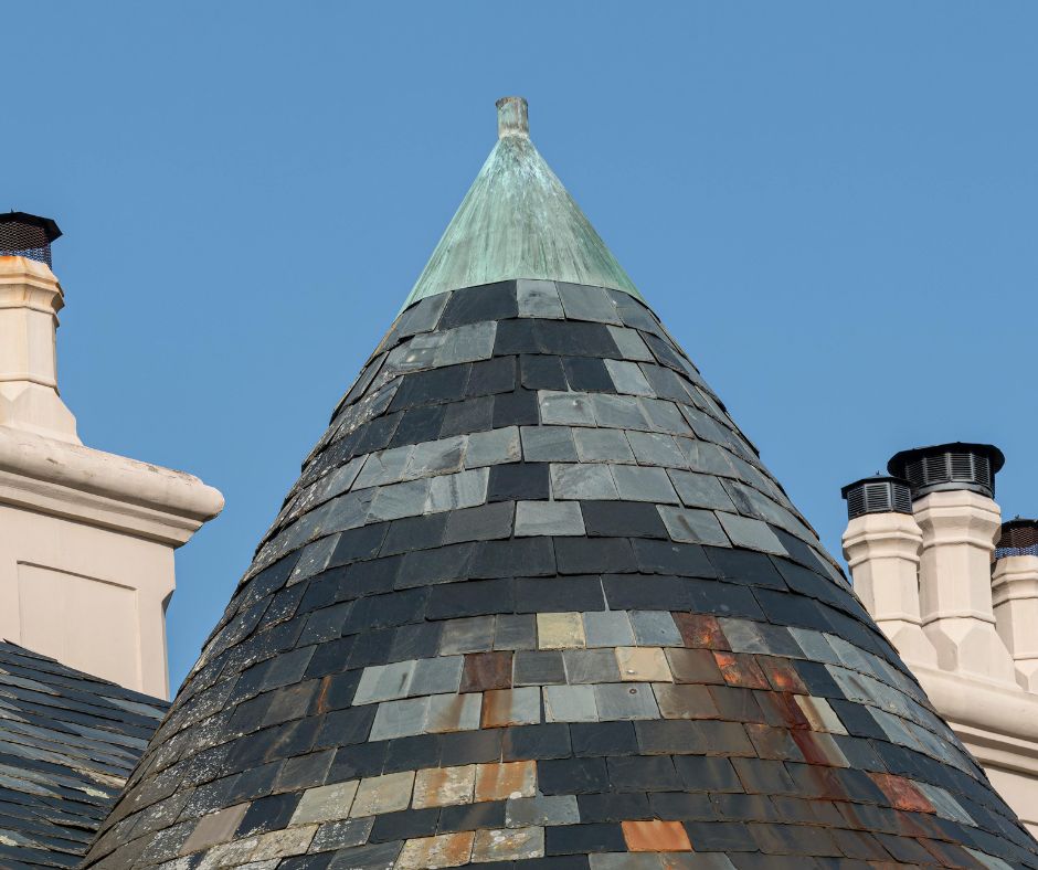 Conical slate turret roof topped with a copper finial on a heritage building